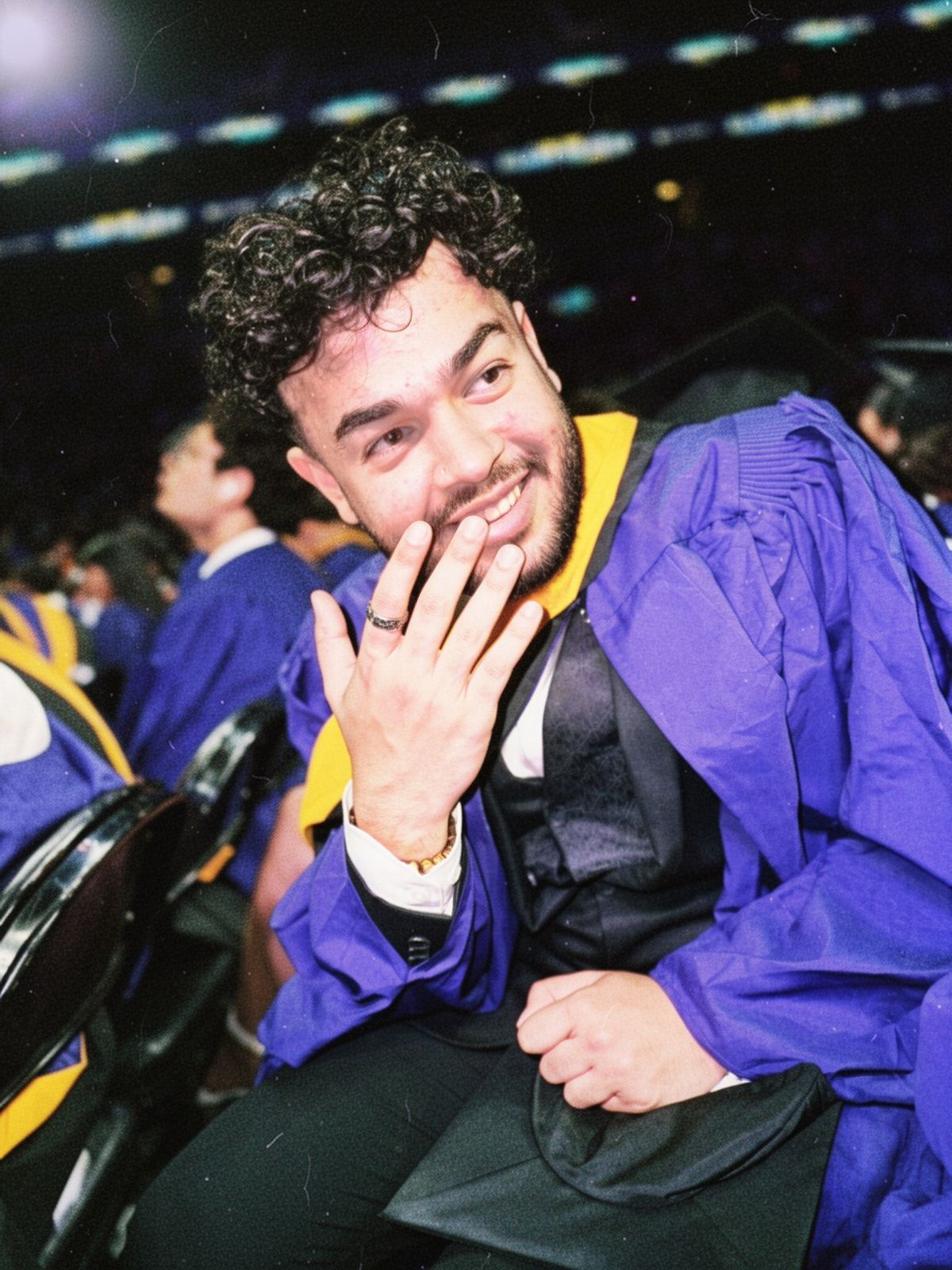 Karthik smiling at graduation in a purple graduation gown